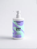 A white pump bottle of Quirk & Co. Sensitive Skin Face & Body Cleanser with a pastel purple and mint green label, set against a clean white background.